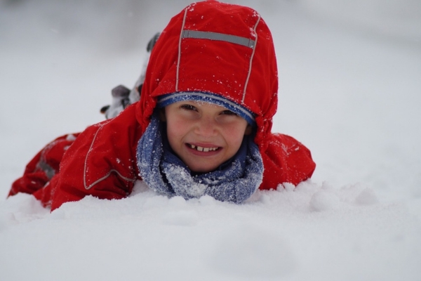 photo of a kid dressed in winter gear playing in the snow