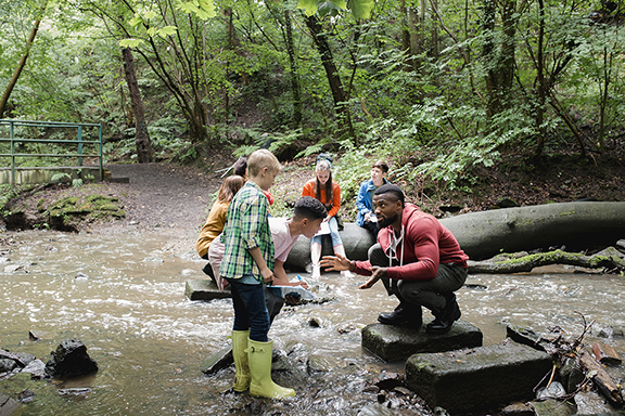 Naturalist in woods showing something to kids